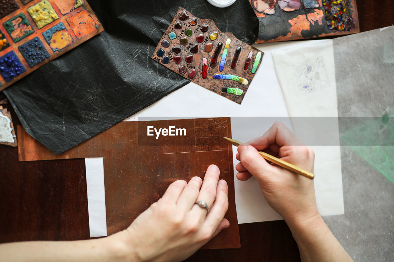 Drawing a sketch on a plate of copper with a metal pen, close-up, materials in a home creative 