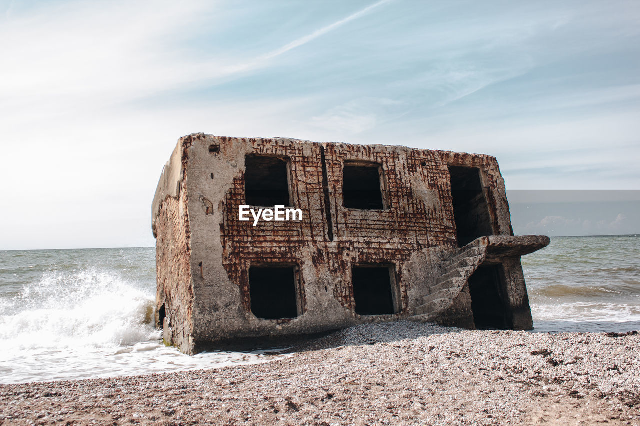 Abandoned built structure on beach against sky