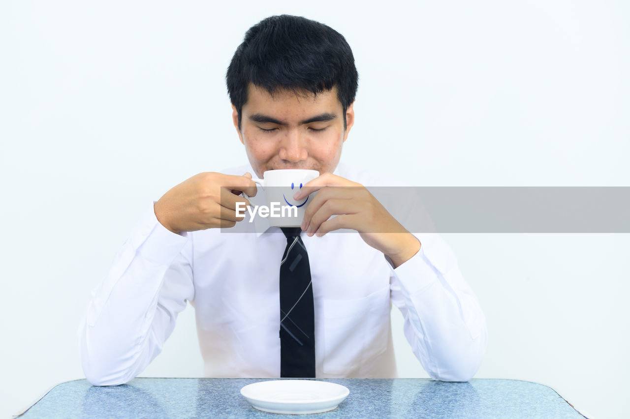 YOUNG MAN DRINKING COFFEE CUP WITH WHITE BACKGROUND