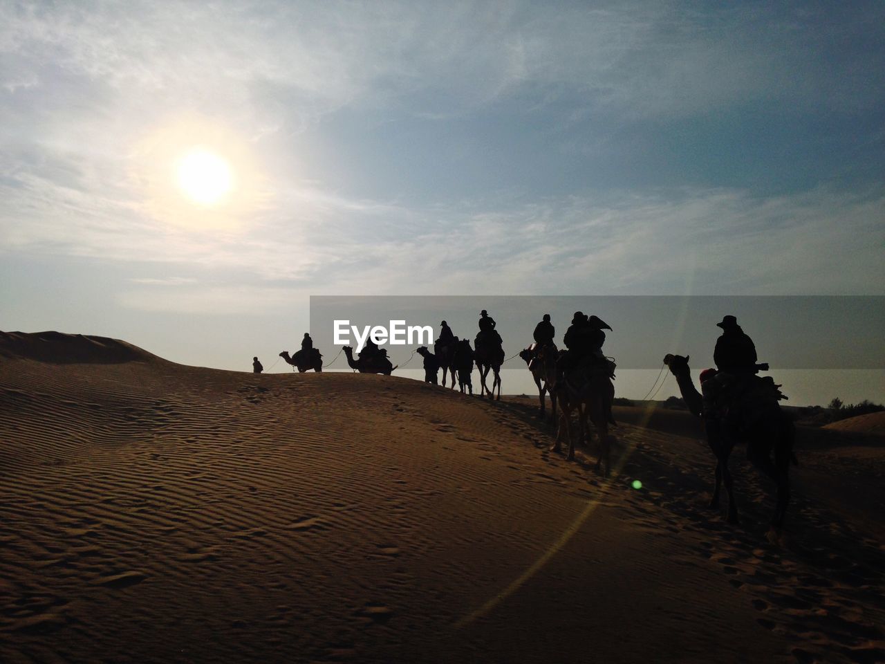 People riding on camels on sand dunes in desert