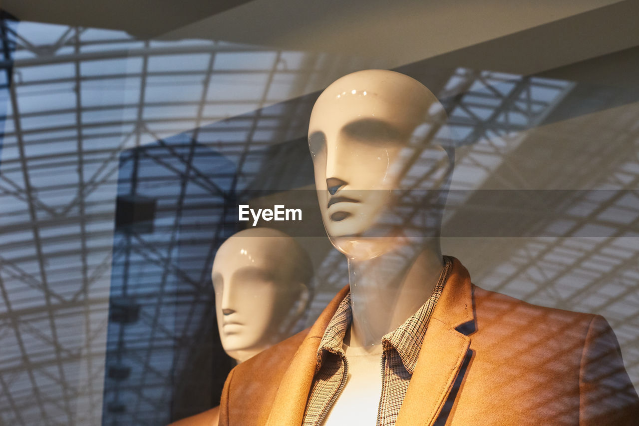 Close-up of mannequins seen through store window