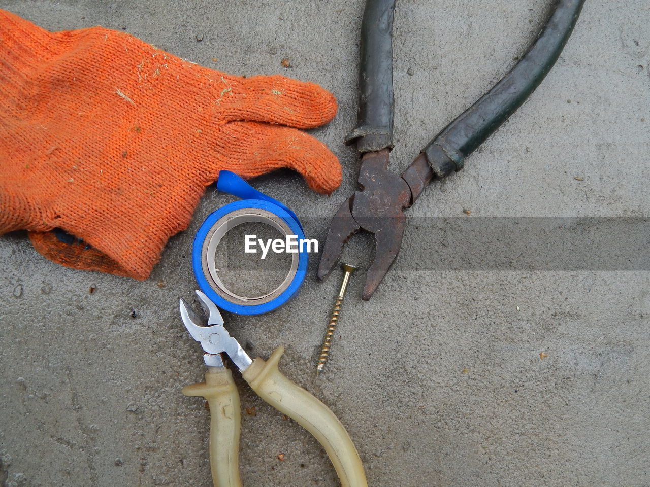 Glove with adhesive tape and hand tools on concrete