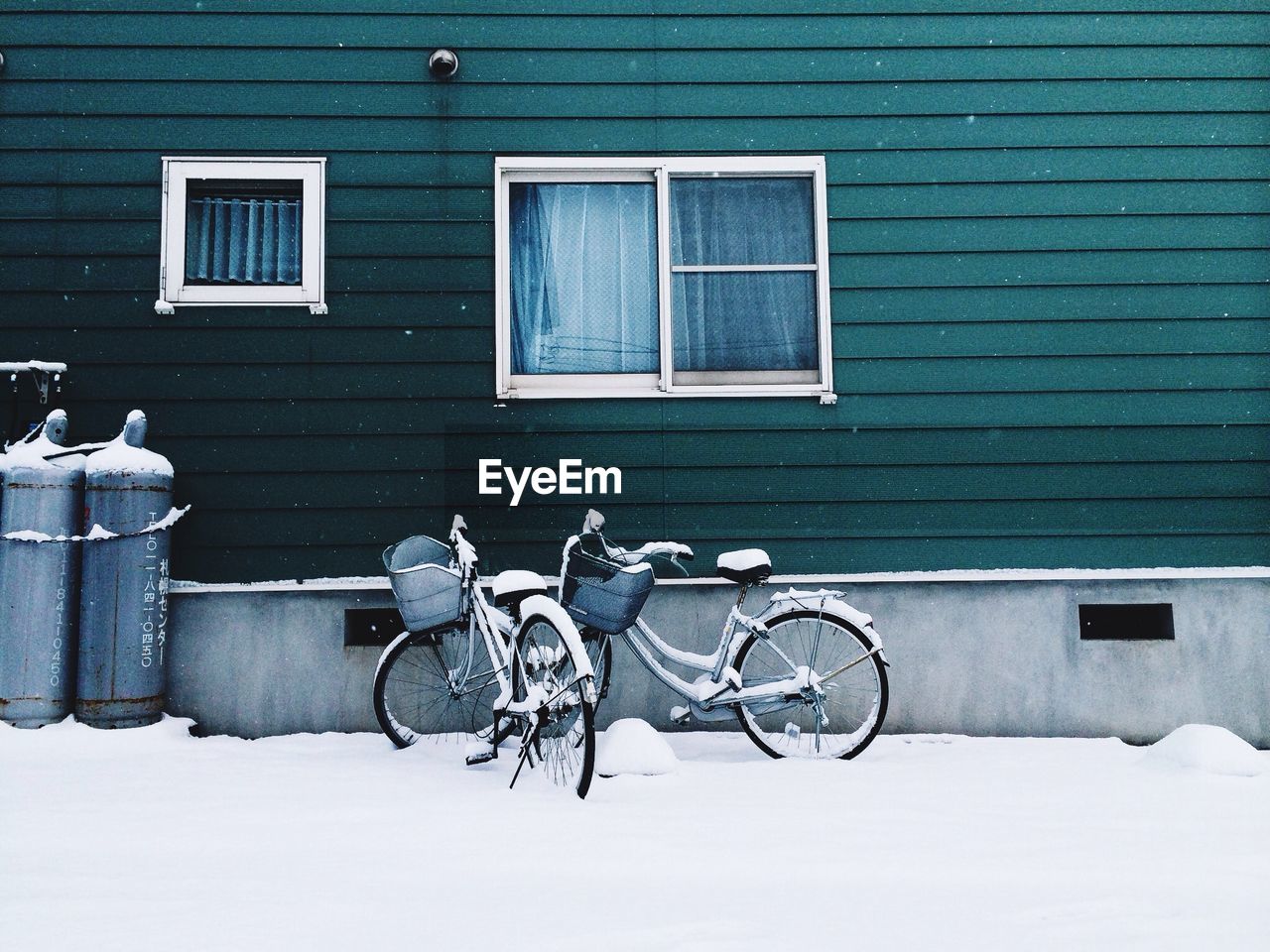 Bicycles parked by house in snow