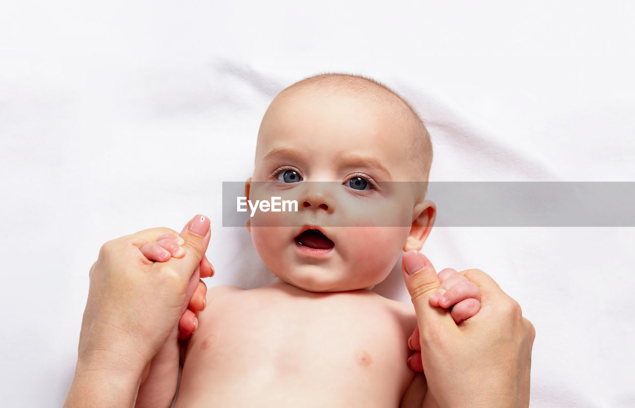 Caucasian funny child in white nappy lies on light background. top view. 