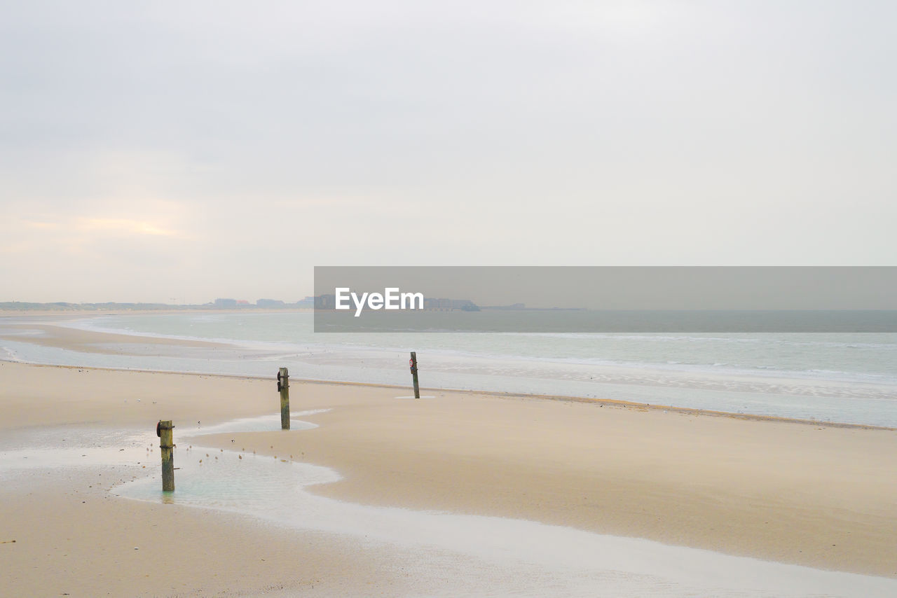 rear view of woman walking on beach against sky during sunset