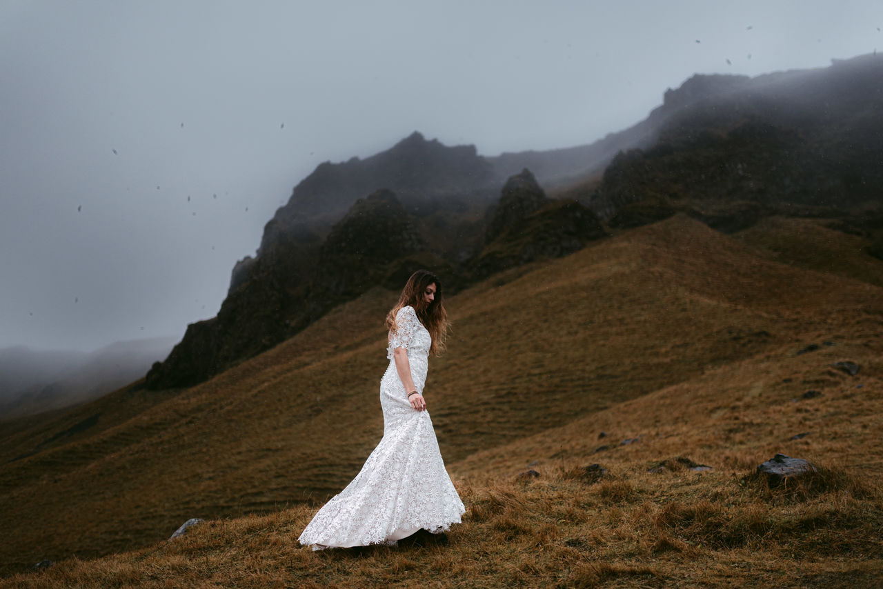 Woman standing on mountain by road against sky