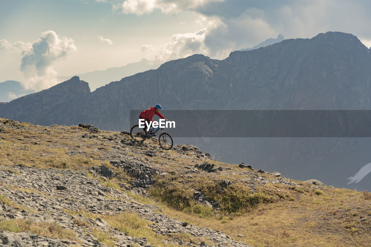 Man riding bicycle on mountain against sky