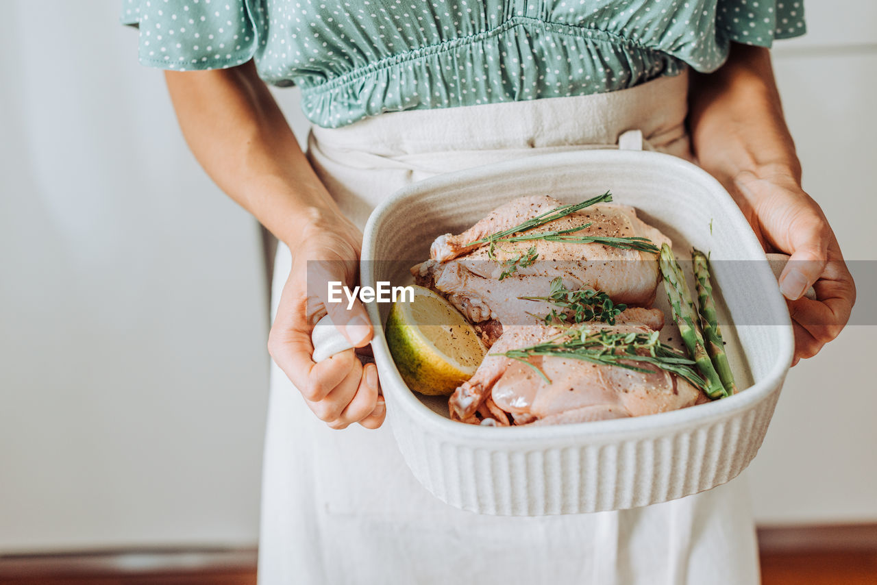 Close up of a tray with raw chicken or quail with aromatic herbs