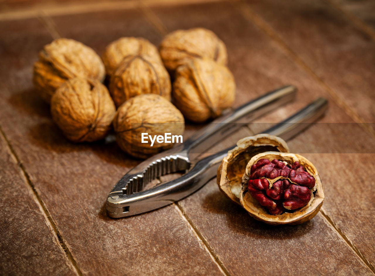 Red danube and juglans regia walnuts on wooden background, comparison concept..