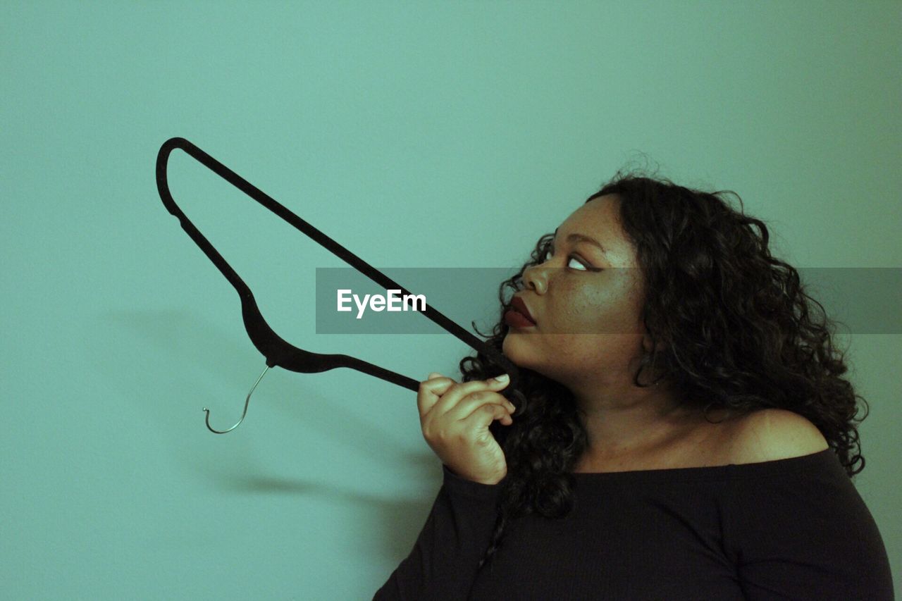Woman holding coathanger against blue wall