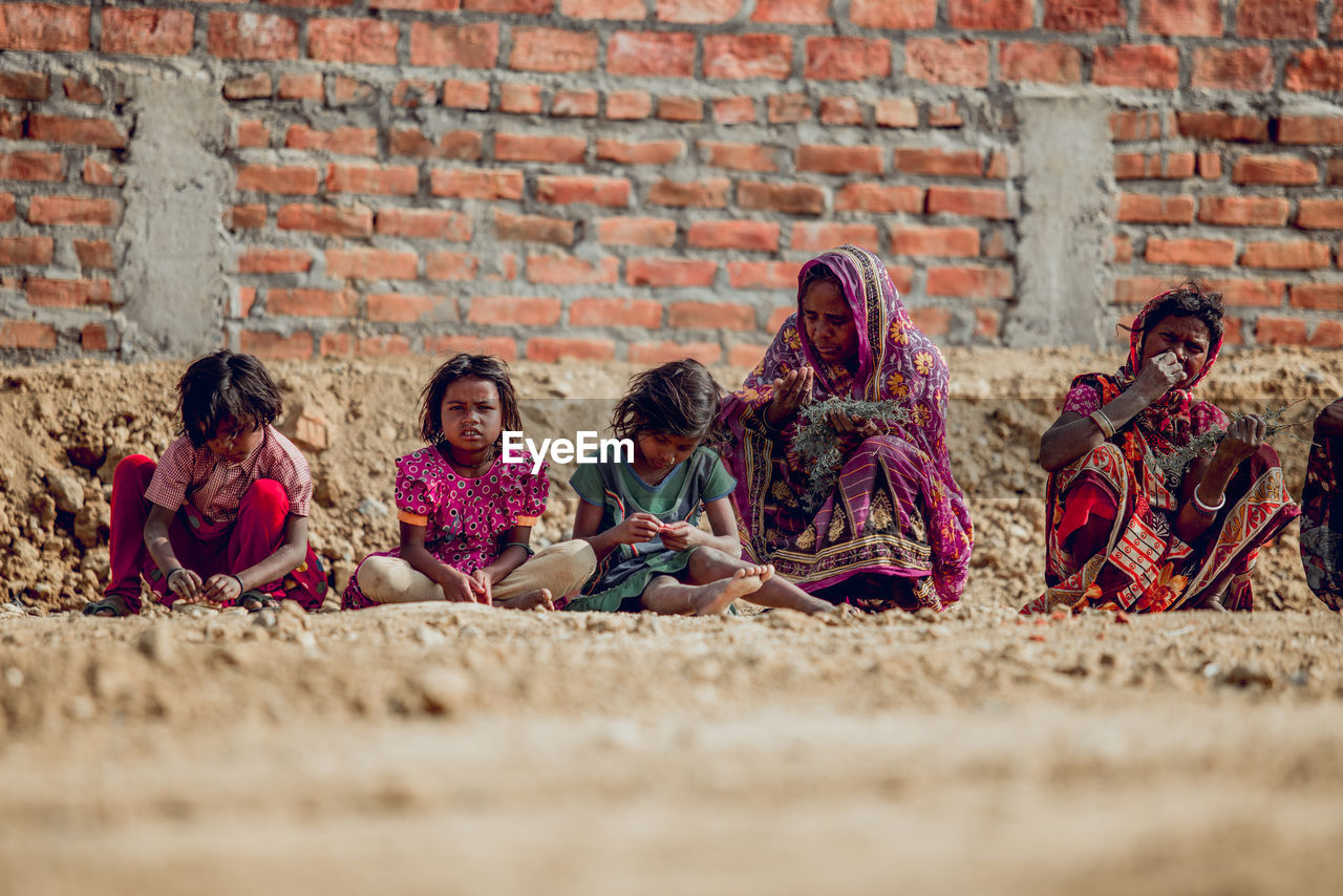 GROUP OF PEOPLE SITTING AGAINST WALL