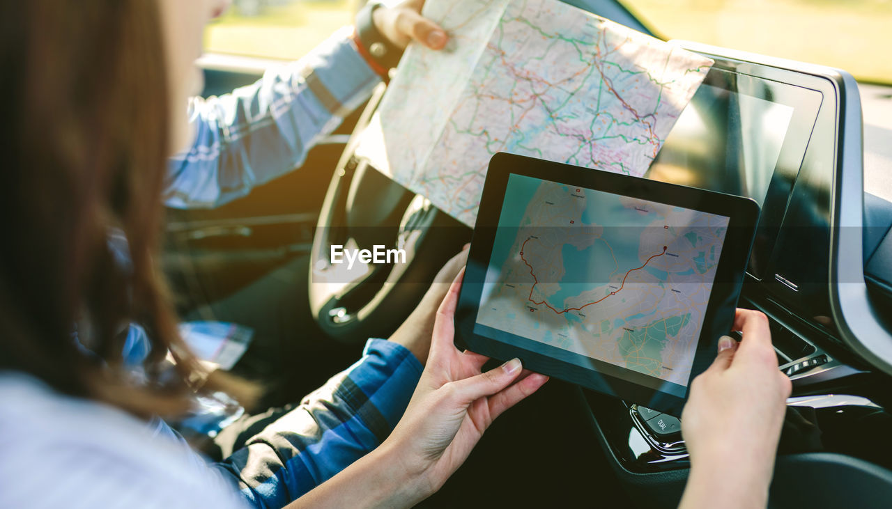 Young couple reading map on digital tablet in car