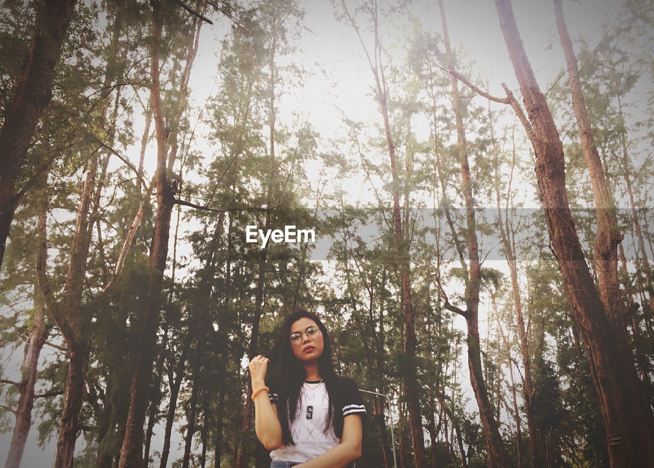 PORTRAIT OF YOUNG WOMAN STANDING IN FOREST