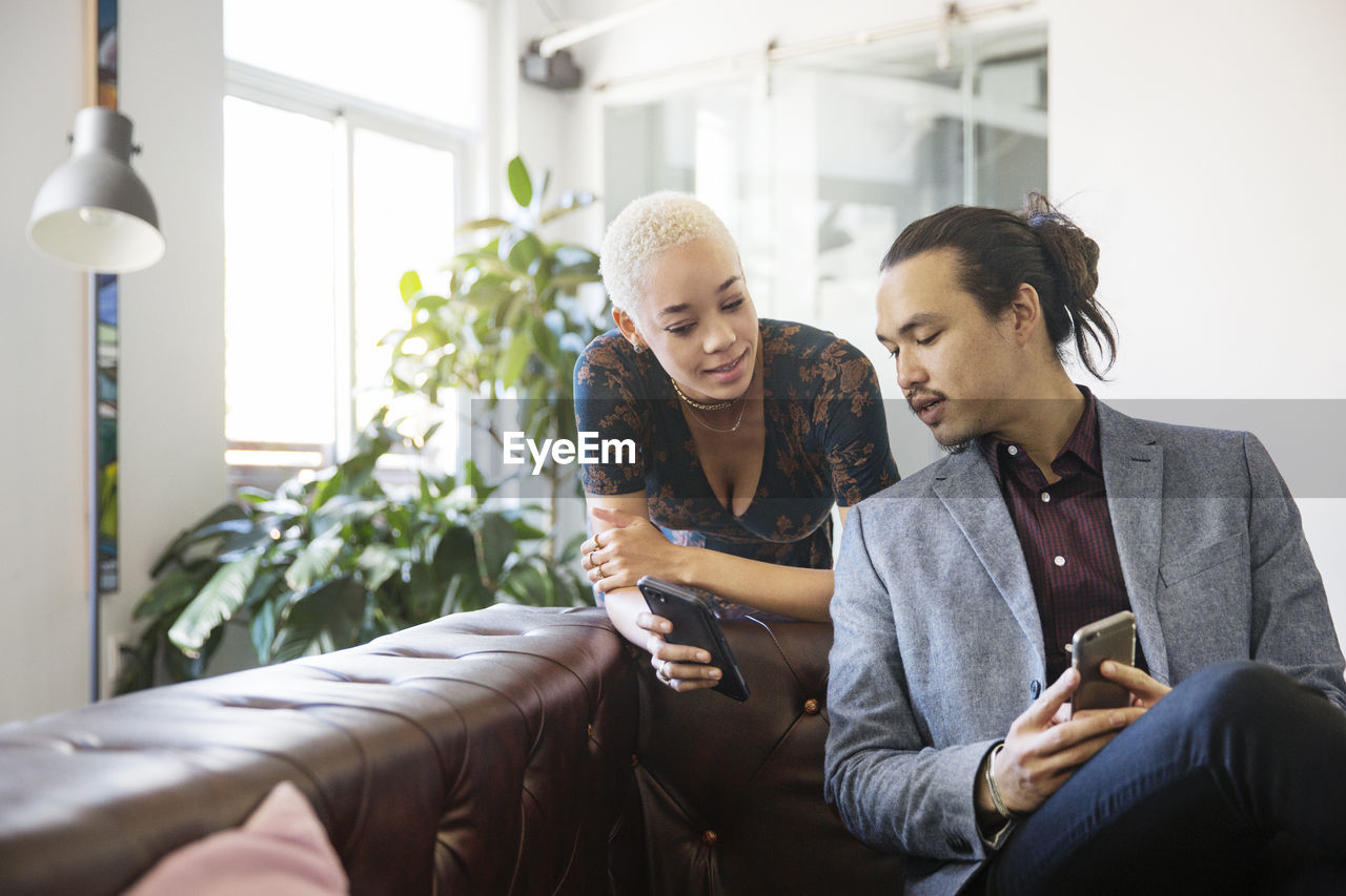 Woman showing mobile phone to colleague in office