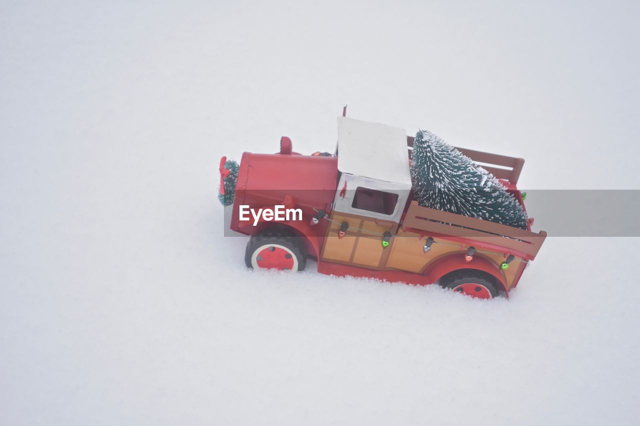 Close-up of toy car with christmas tree figurine on snow