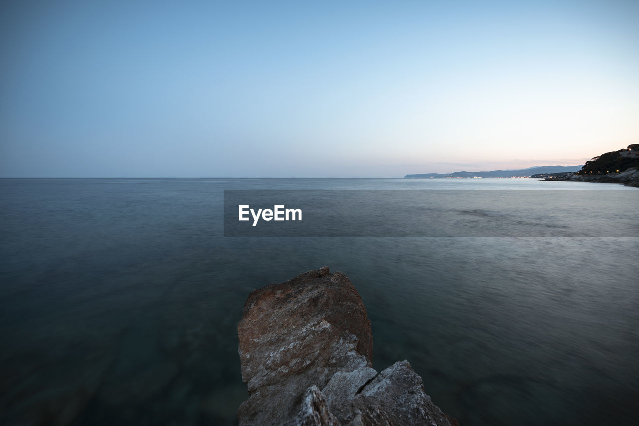 SCENIC VIEW OF ROCKS AT SEA AGAINST CLEAR SKY