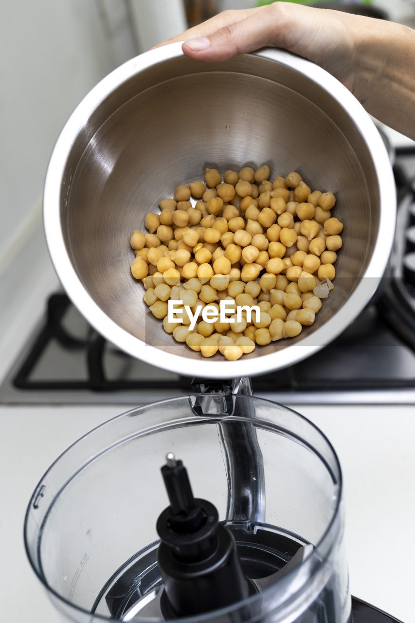 Chickpea in a bowl and food processor for making hummus.