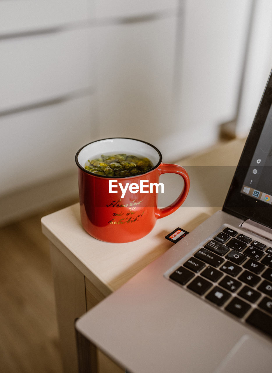 CLOSE-UP OF DRINK WITH LAPTOP ON TABLE