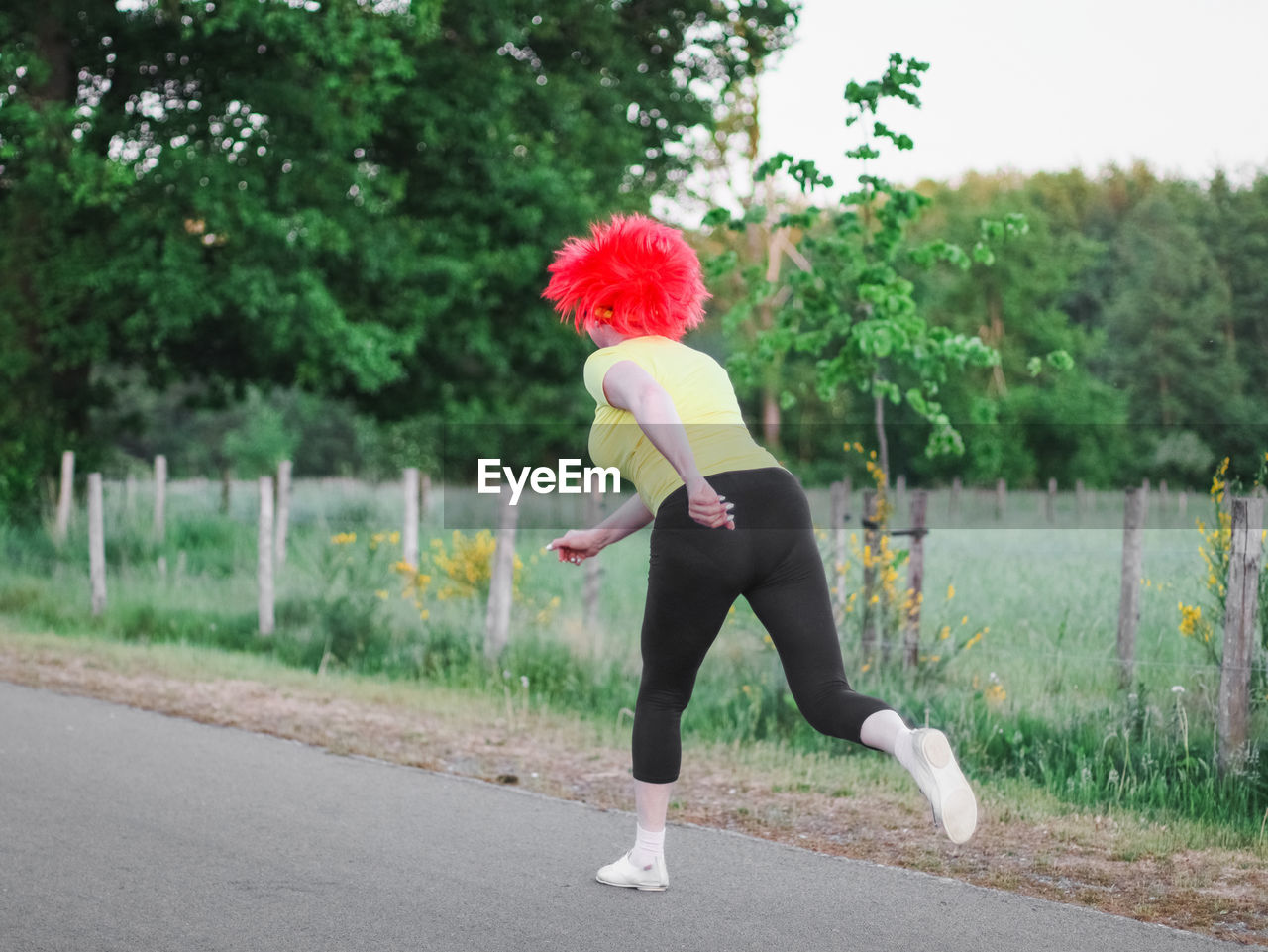 Caucasian woman runner in a belgian flag wig runs in a funny marathon.