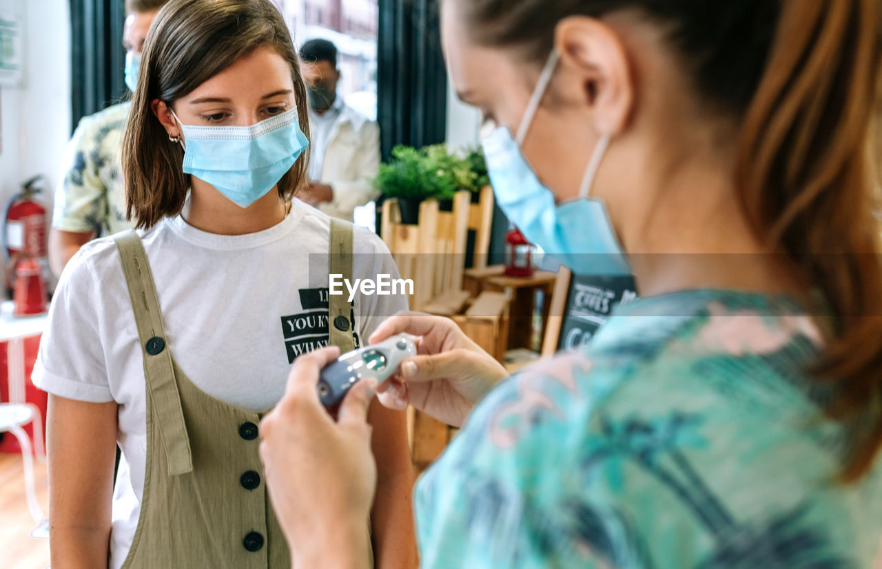 Woman checking temperature of woman in restaurant