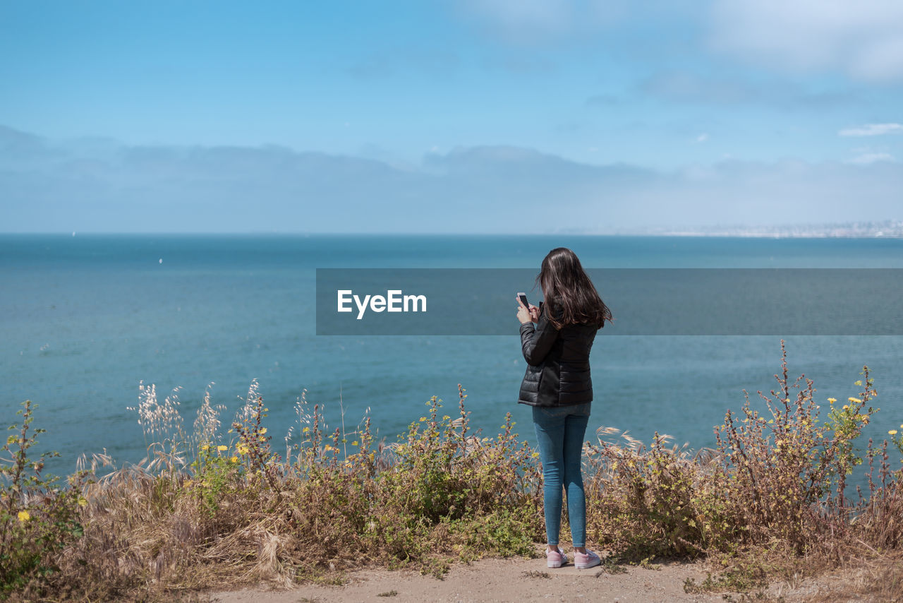 Full length of woman standing on sea shore against sky