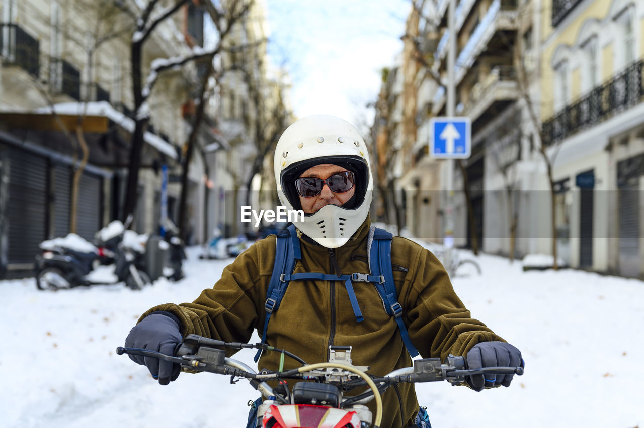 Close-up of a man sitting with his vintage motorcycle on the street.