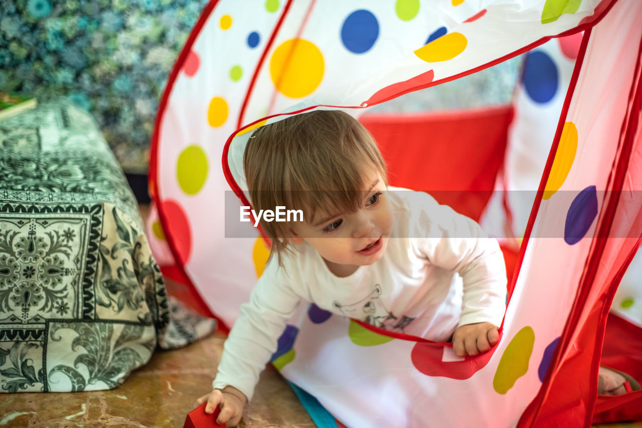 Cute baby girl looking away while sitting in tent