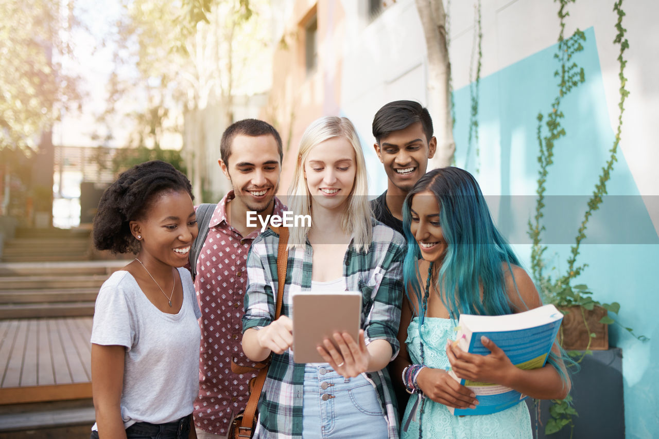 Cheerful friends talking on video call outdoors