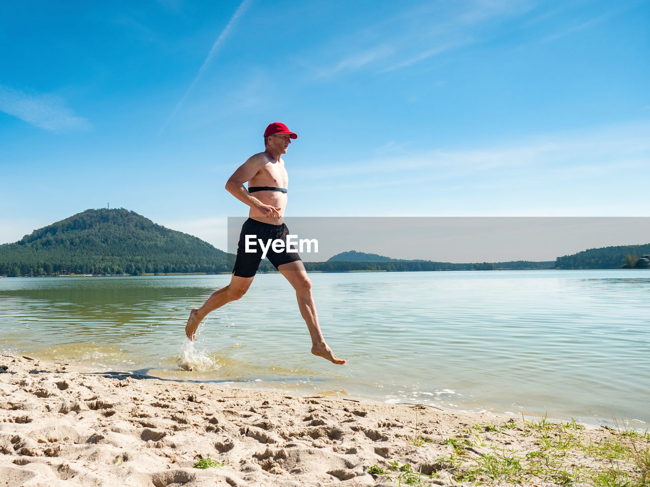 Runner run in water at beach, drops refreshing his body. runner with heart rate monitor  smart watch