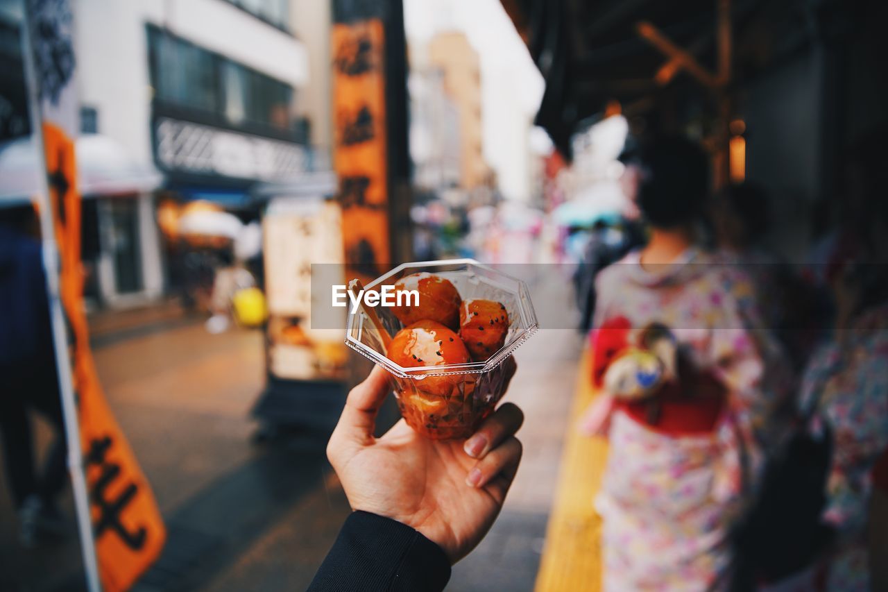 Midsection of man holding ice cream in city