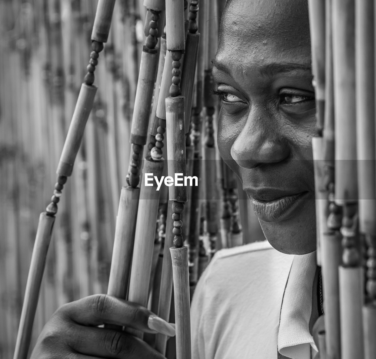 Ghana woman looking out from a bar outside accra with bamboo drapery, maybe time to go home.