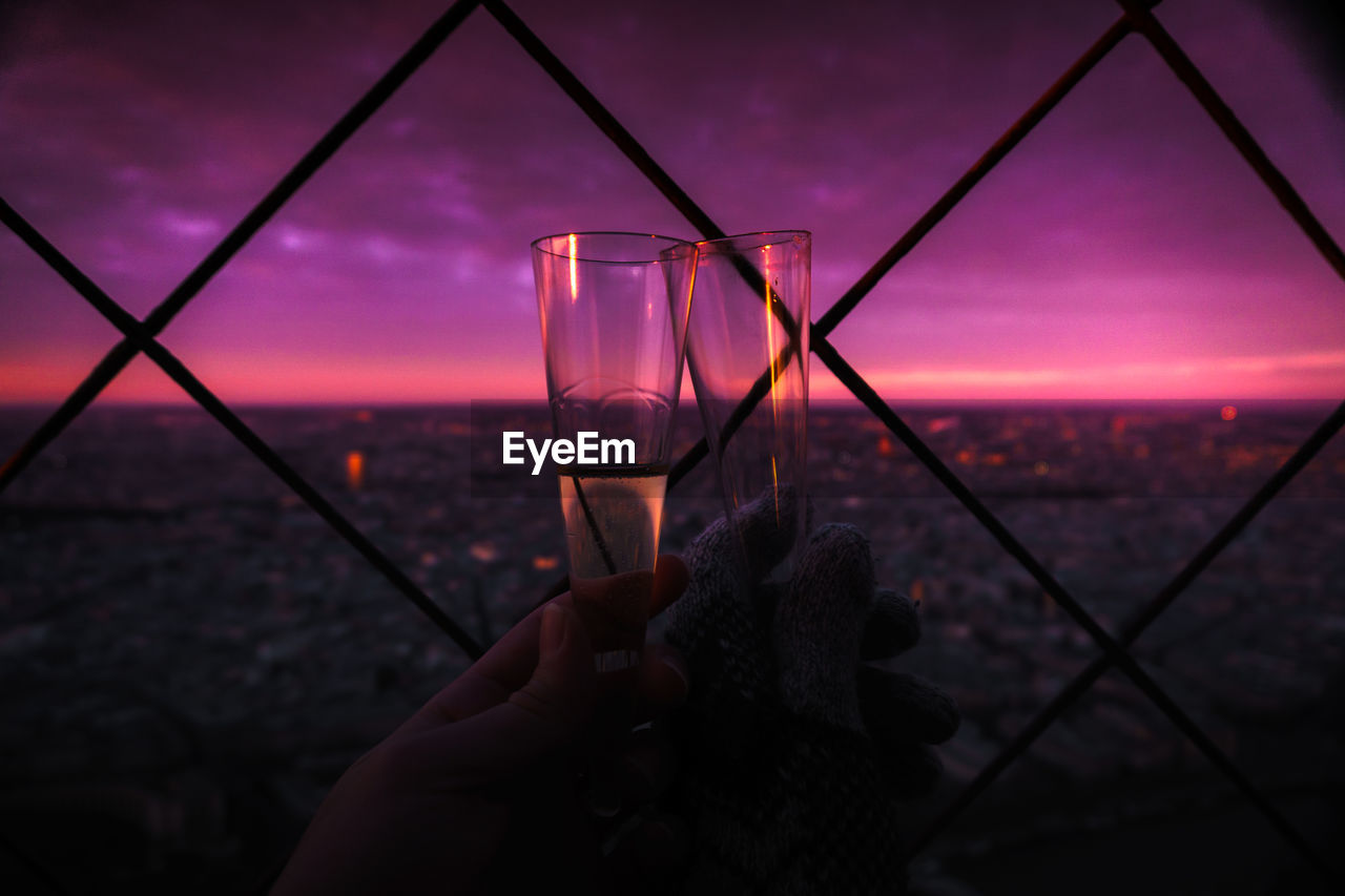 Cropped image of people toasting champagne flutes against sky at twilight