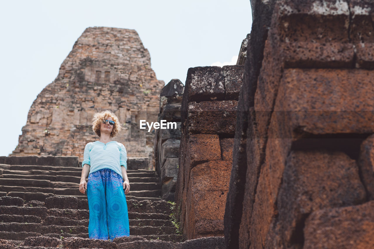 Low angle view of woman standing on steps at old ruin