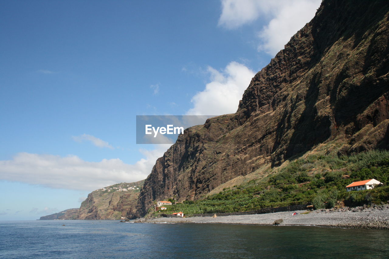 Scenic view of sea and mountains against cloudy sky