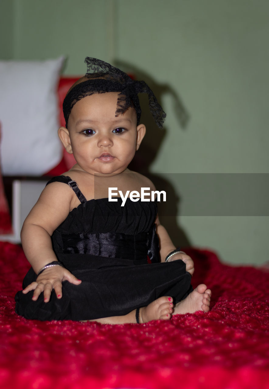 Full length of baby girl sitting on bed