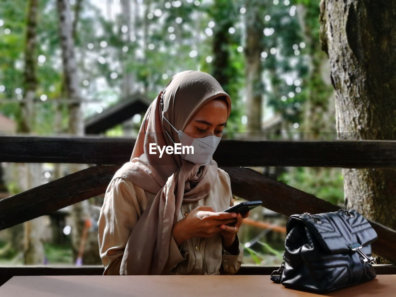 Portrait of woman using mobile phone while sitting in park