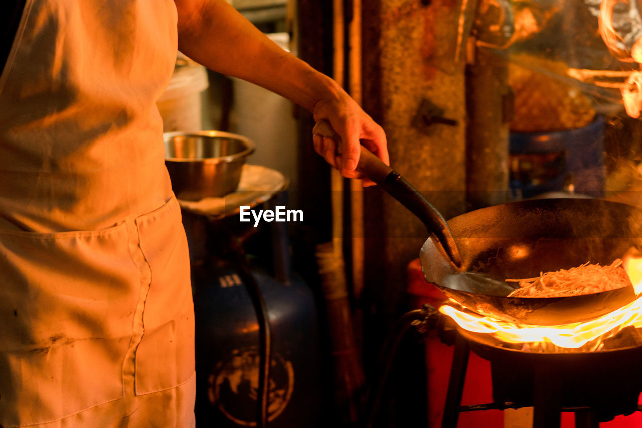 Midsection of chef preparing food in commercial kitchen