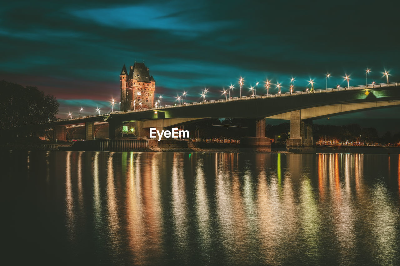 Illuminated bridge over river against sky in city at night