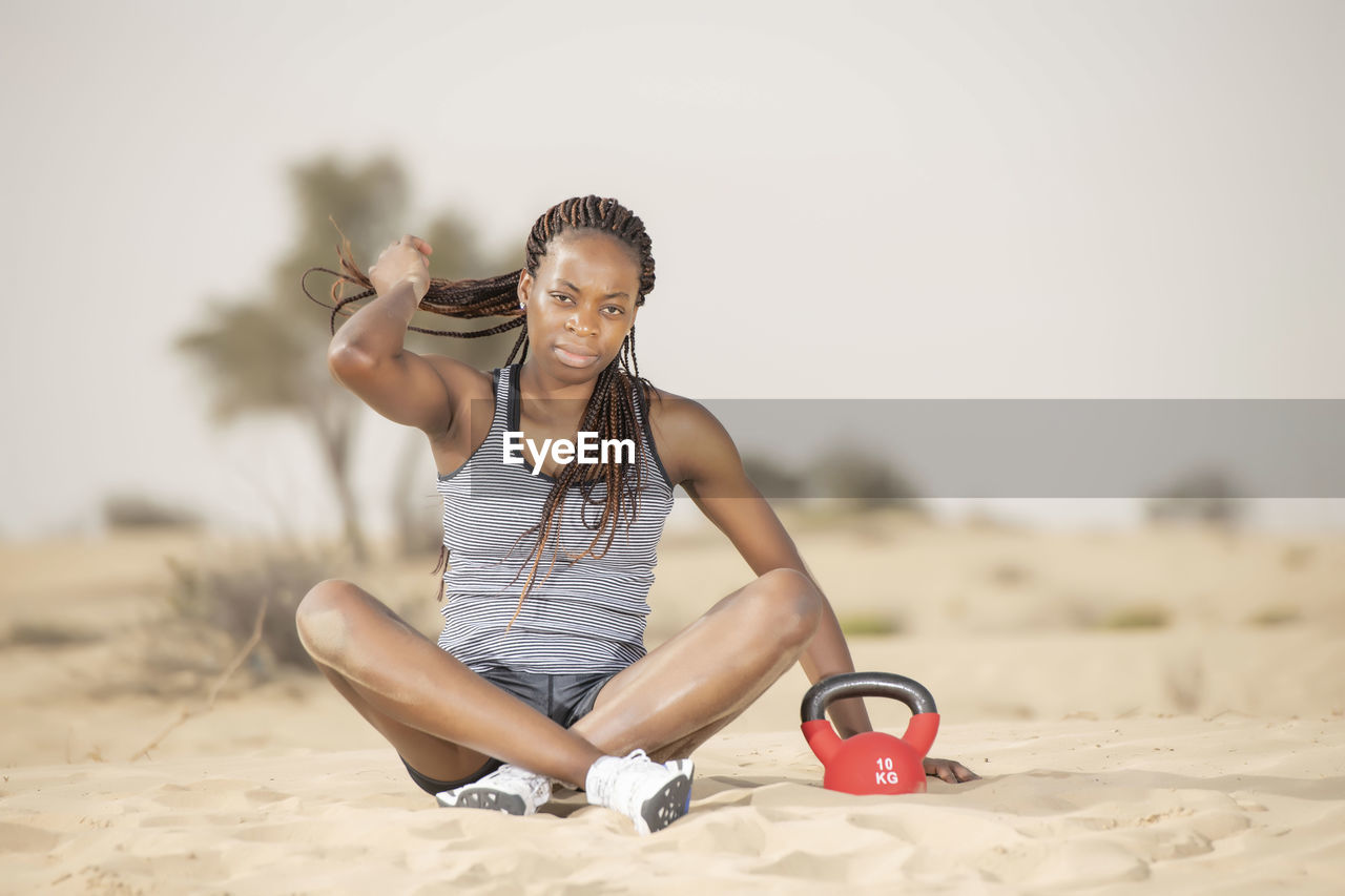 Full length of woman exercising in desert against sky