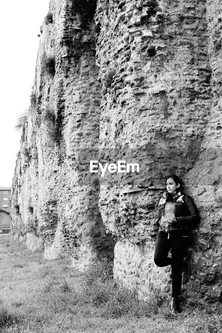 Full length of woman standing against wall