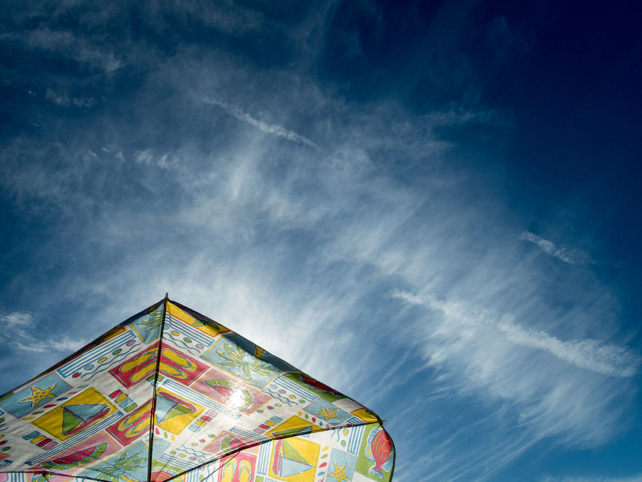 Low angle view of multi colored umbrella against blue sky