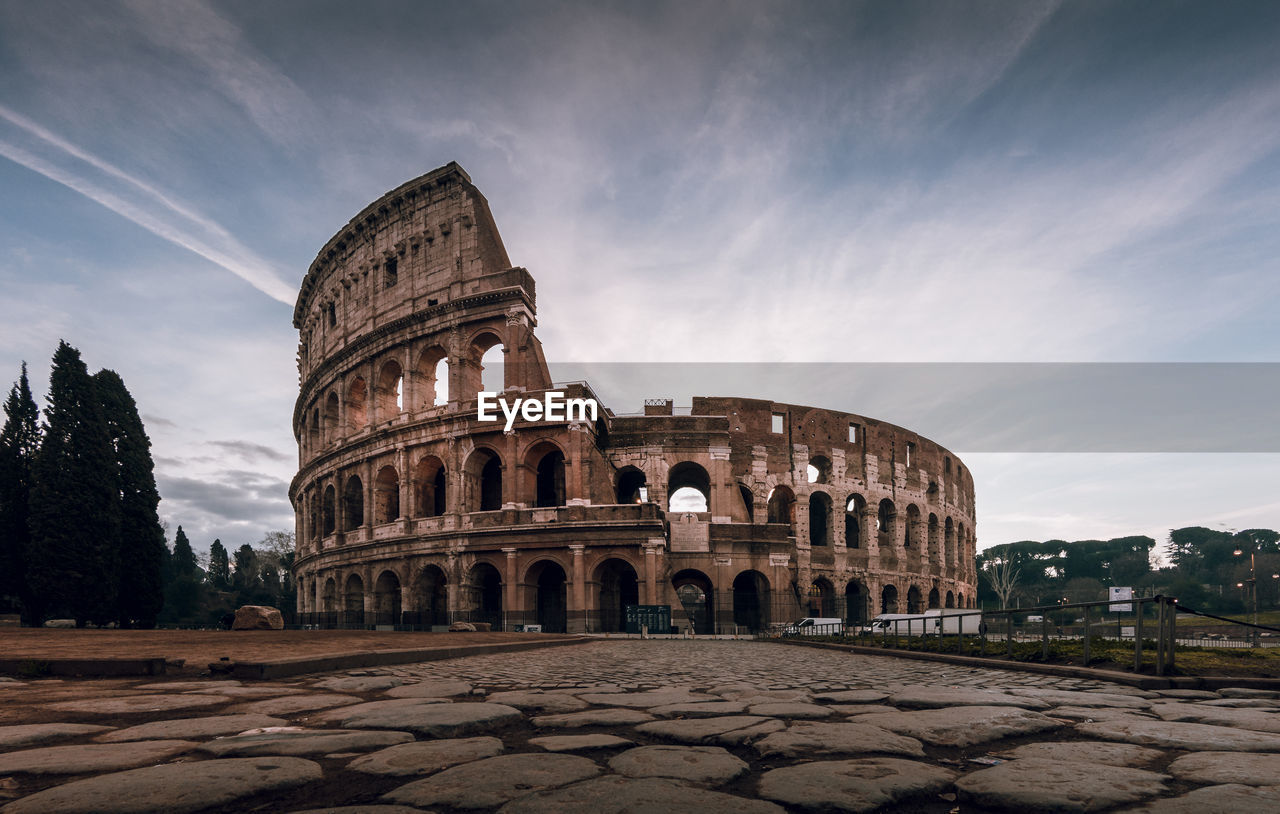 Surface level image of coliseum against sky during sunset