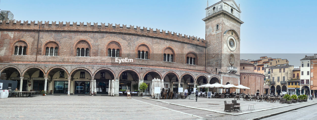  extra wide view of  square of erbe in mantua with historical buildings and a beautiful clock tower
