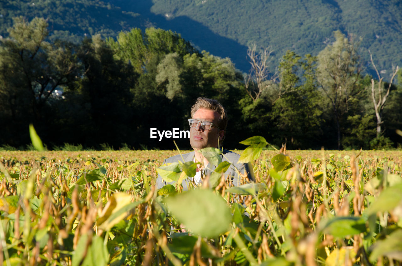 Mature man amidst plants on field