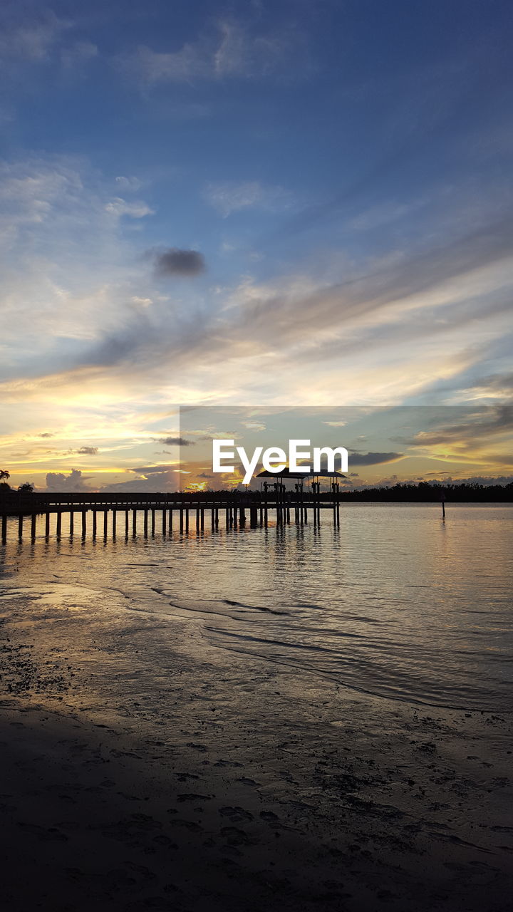 PIER ON BEACH AGAINST SKY DURING SUNSET