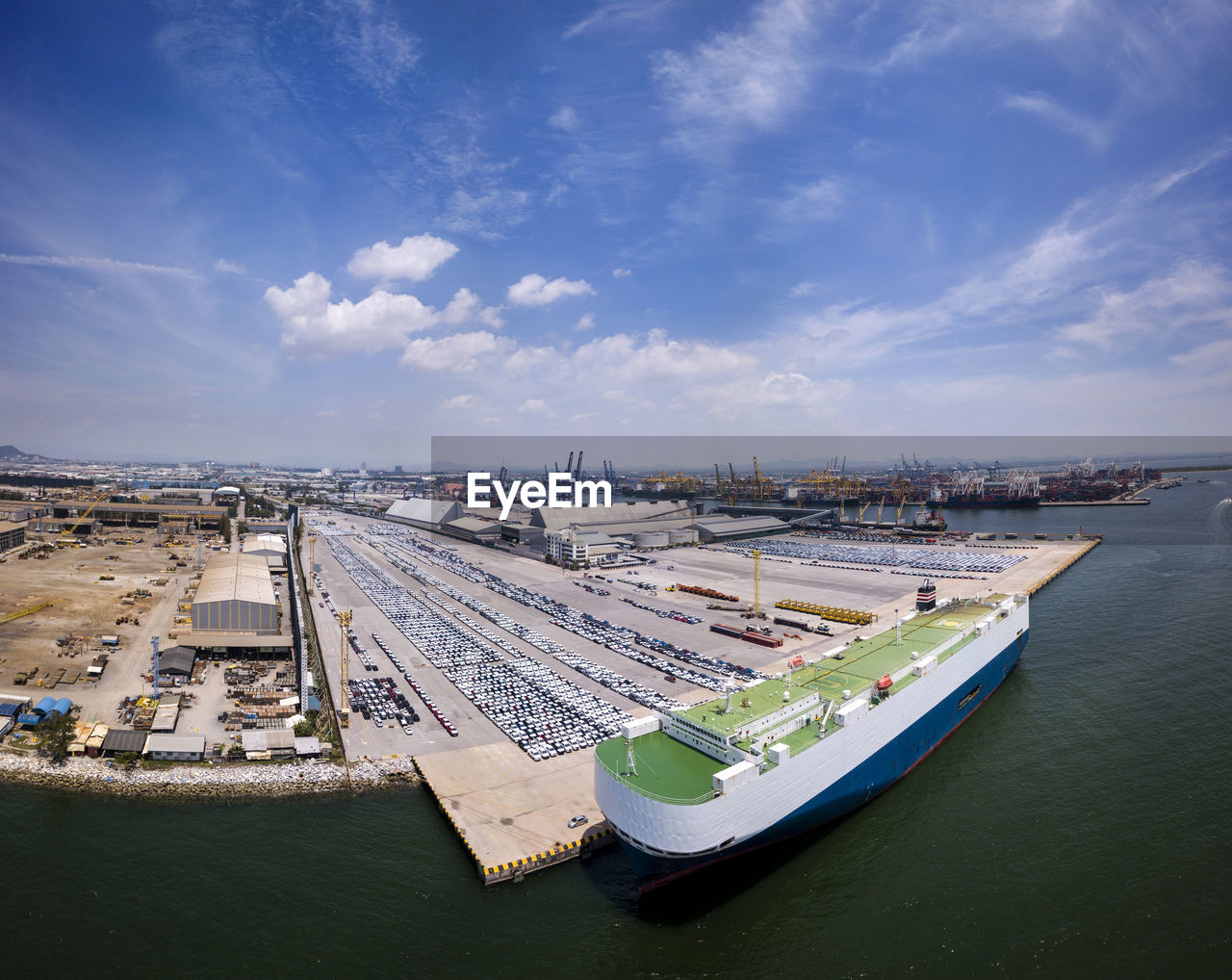 Aerial logistics commercial vehicles waiting to be load on to a car carrier ship at dockyard