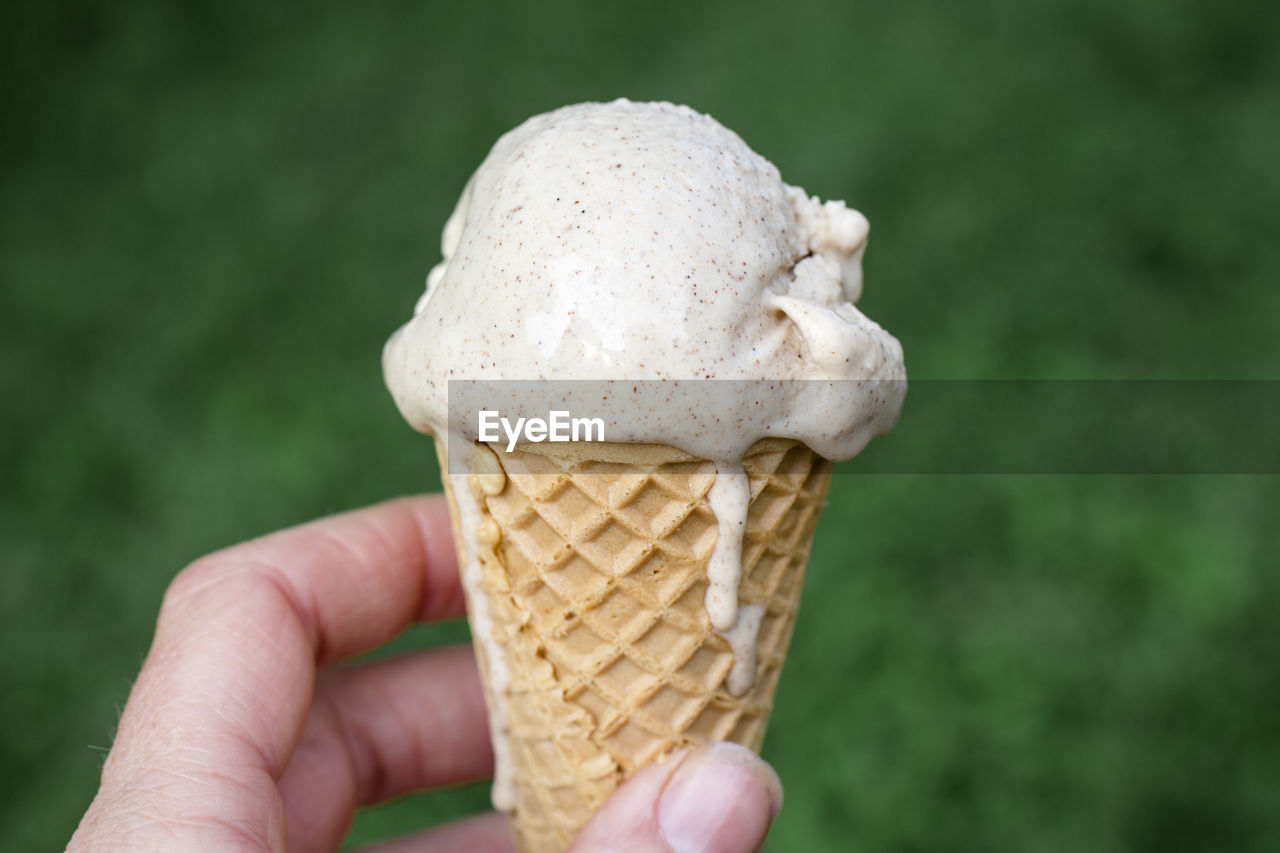 Close-up of a dripping ice dream cone in a hand