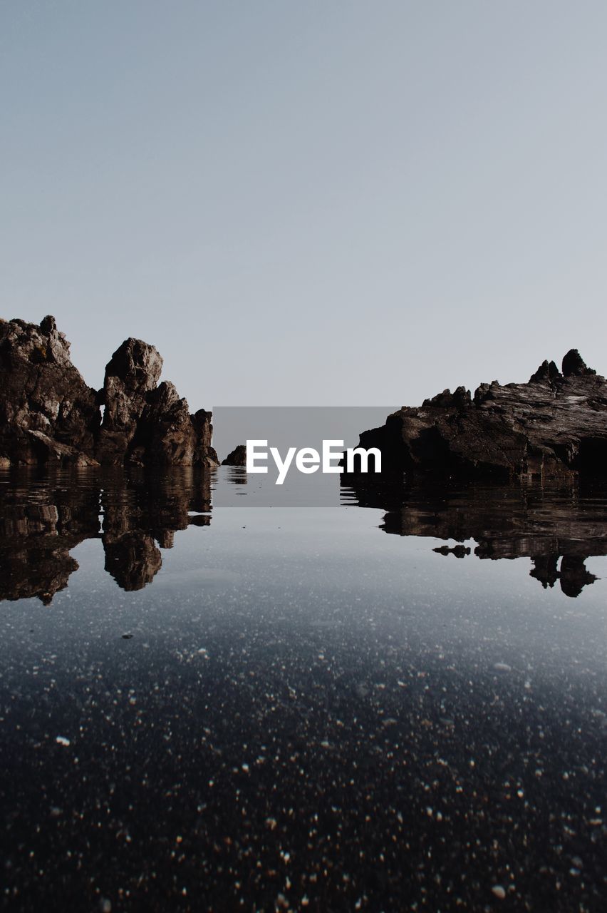 Rock formations in water against clear sky