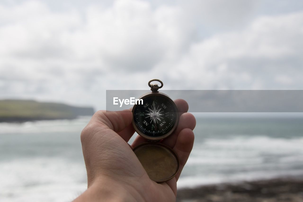 Cropped image of hand holding compass