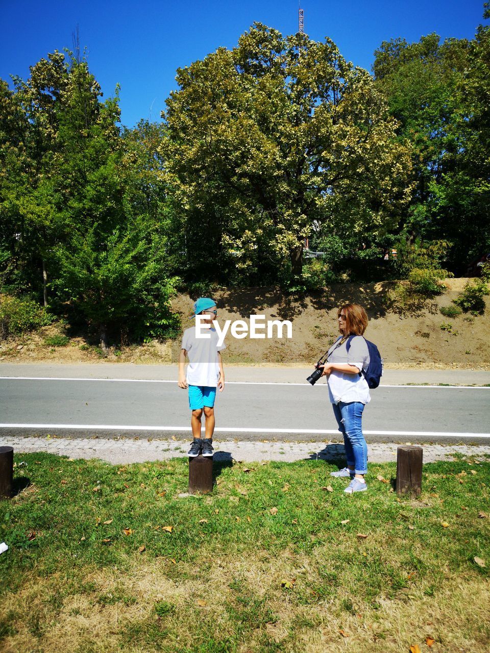 Mother with camera standing by son on grassy field